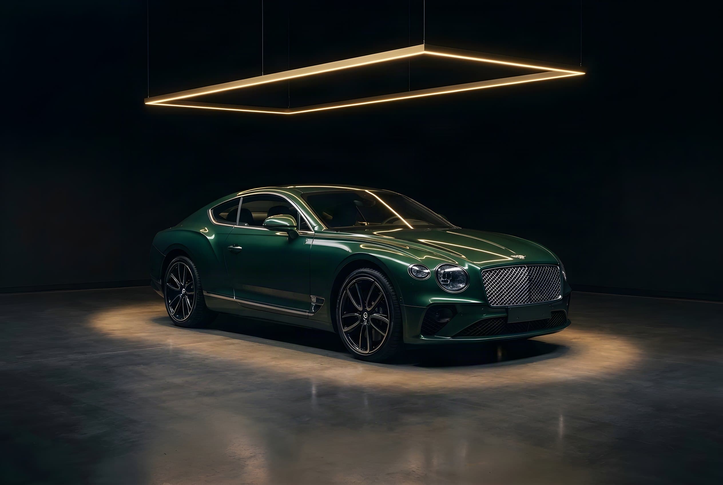 Dark green Bentley Continental GT beneath a golden light frame in a dark room