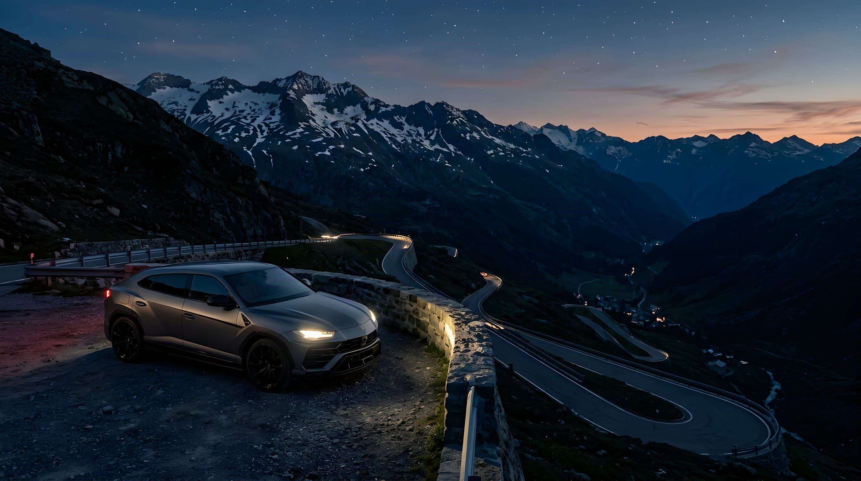 Grey SUV at dusk on a pass road above a valley with hairpin bends